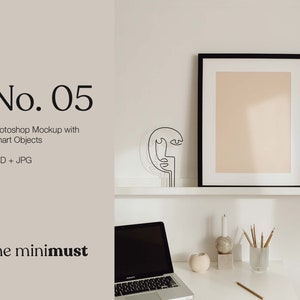 Puede incluir: Una maqueta de póster enmarcada en negro con un passe-partout blanco, una escultura de alambre negro de una cara, un portátil, un candelero blanco, un objeto redondo de piedra, un jarrón con lápices y un escritorio blanco.