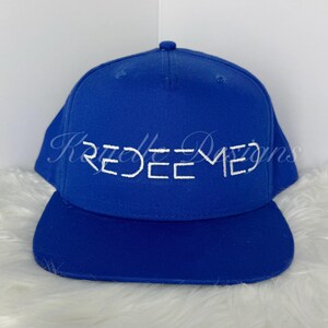 Puede incluir: Una gorra de béisbol azul real con un logotipo bordado en blanco que dice "REDEEMED".