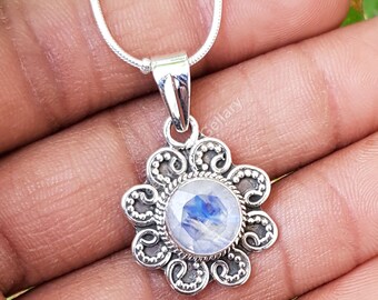 May include: A silver pendant necklace featuring a round, iridescent moonstone set in a decorative, floral-inspired frame. The pendant hangs from a delicate silver chain, showcasing a classic and elegant design. The moonstone displays blue and white hues.