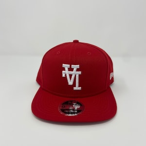 May include: A red baseball cap with a white "LA" logo on the front. The cap is a New Era Snapback.