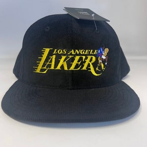 May include: Black corduroy baseball cap with a gold embroidered Los Angeles Lakers logo and a small basketball player graphic.