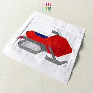 May include: A red, gray, and blue patchwork quilt block with a geometric design. The block is on a white background.
