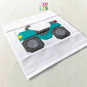 May include: A teal and gray patchwork quilt block depicting a tractor. The block is sewn onto a white background.