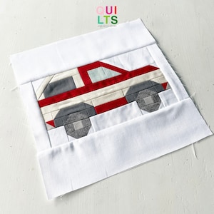 以下が含まれることがあります： 赤、白、グレーのパッチワークキルトブロックで、車のデザインが施されています。ブロックは白い縁取りで囲まれています。