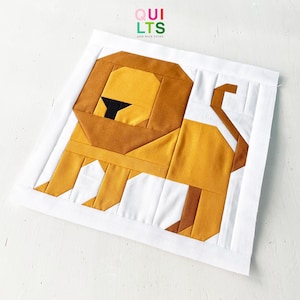 May include: A geometric patchwork lion design in shades of gold, brown, and black, set against a white background. The lion is made of fabric pieces, with the text "QUILTS AND NICE STUFF" in the upper right corner.