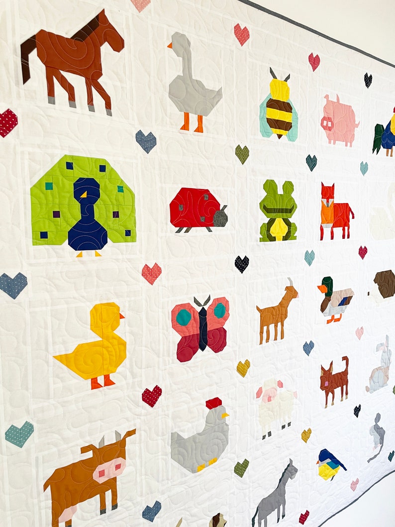 May include: A white quilt featuring a variety of colourful animal and insect designs. The quilt includes a horse, goose, bee, pig, peacock, ladybug, frog, fox, goat, duck, butterfly, chicken, cow, sheep, donkey, and a bluebird.