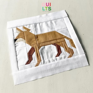 Könnte beinhalten: Ein weißer Stoffquadrat mit einem geometrischen Fuchsdesign in Braun, Weiß und Rot. Der Stoffquadrat ist von einem weißen Rand umgeben.