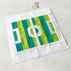May include: A white fabric square with a green and white geometric pattern inside. The fabric square has a white border and the text "OUI LTSS AND NICE STUFF" is printed in the top center.
