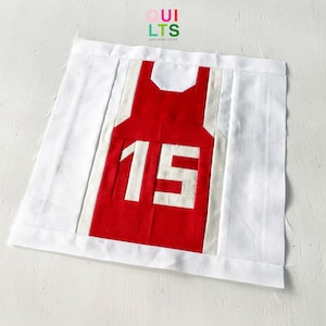 May include: A red and white quilted fabric jersey with the number 15 on the front.