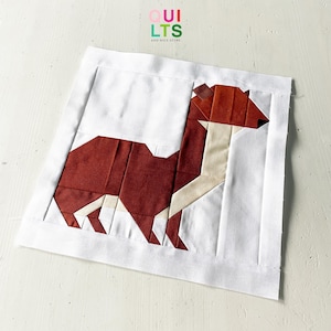Könnte beinhalten: Ein brauner und weißer geometrischer Patchwork-Quiltblock, der ein stilisiertes Tier darstellt, möglicherweise einen Fuchs oder einen Hund. Der Block ist vor einem weißen Hintergrund platziert.