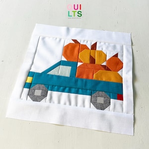 Peut inclure: Un bloc de courtepointe en tissu carré représentant un camion sarcelle transportant des citrouilles orange et jaunes. Le motif est encadré par une bordure blanche. Le camion a des roues gris foncé avec des centres gris clair, un phare jaune et un feu arrière rouge.