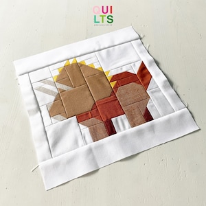 May include: A patchwork quilt block featuring a horse design in shades of brown, rust, and tan, with yellow accents. The block is framed by a white border and includes the text "Quilts and Nice Stuff" in the upper right corner.