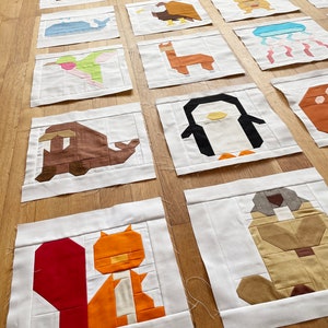 May include: A collection of 16 colourful fabric squares featuring different animal designs. Each square is made of various fabric pieces sewn together to create a pixelated look. The animals include a penguin, a squirrel, a hummingbird, a llama, a whale, a jellyfish, a kangaroo, an eagle, a dog, a turtle, a deer, a fish, and a few others.