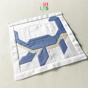 May include: A blue and white geometric quilt block with the text "QUI LTS AND NICE STUFF" in the top center.
