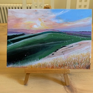 May include: A painting depicting a rolling green hillside with a white sky and pink clouds in the background. The hillside is covered in green grass and there are some white sheep in the distance.