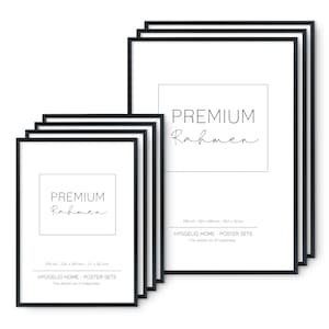 May include: A set of six black picture frames with white mats. The frames are stacked on top of each other. The largest frame is labeled "PREMIUM Rahmen" and has the dimensions 29.7 x 42 cm. The smaller frame is labeled "PREMIUM Rahmen" and has the dimensions 21 x 29.7 cm. The text "HYGGELIG HOME - POSTER SETS - The danish art of happiness -" is printed below the dimensions.