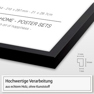 May include: A black picture frame with a white mat and a white background. The frame is 21 inches by 29.7 inches and is made of real wood. The text "HOME - POSTER SETS" and "h art of happiness -" is printed on the white background. The text "Hochwertige Verarbeitung aus echtem Holz, ohne Kunststoff" is printed on a white rectangle at the bottom of the image.