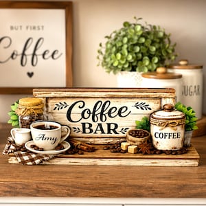 May include: A rustic wooden coffee bar sign with the words "Coffee BAR" in black script. The display includes a coffee cup with the name "Amy", coffee beans, a small creamer, and a jar of coffee beans. A sign that says "But First Coffee" is in the background.