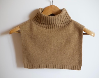 May include: A brown knitted turtleneck collar, hanging on a wooden hanger against a white background.