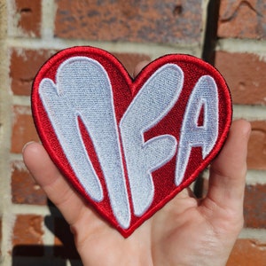 May include: Red felt heart-shaped patch with white embroidered letters spelling "MFA".