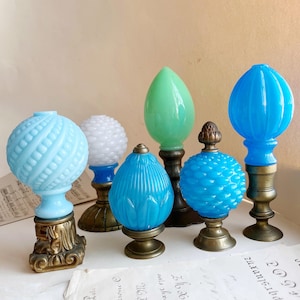 Könnte beinhalten: Eine Sammlung von sechs dekorativen Glasknauf in verschiedenen Blautönen und Grüntönen. Die Knauf sind auf Messingsockeln montiert und weisen unterschiedliche Muster und Texturen auf.