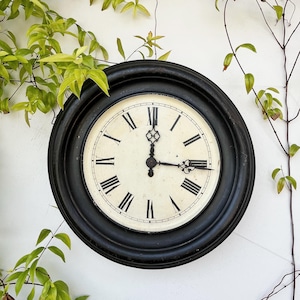 Reloj de pared antiguo de metal de principios del siglo XX con esfera blanca y números romanos (sin llave). Reloj de péndulo (no se ha comprobado su funcionamiento).