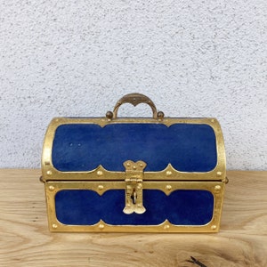 May include: A blue velvet treasure chest with gold accents and a brass lock. The chest has a rounded top and a hinged lid.