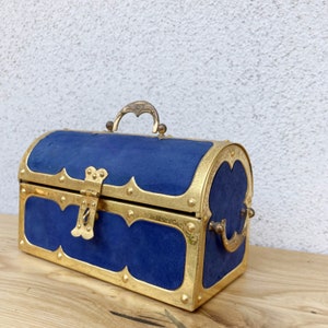 May include: A blue velvet treasure chest with gold accents and a brass handle. The chest has a hinged lid and a decorative lock.
