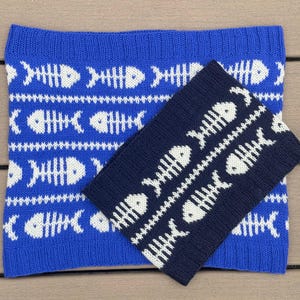 Puede incluir: Dos artículos de punto: un cuello azul y un calentador de cuello azul marino. Ambos presentan un patrón repetido de espinas de pescado blancas. El cuello es rectangular, mientras que el calentador de cuello es un rectángulo más pequeño. Los artículos están hechos de hilo suave y texturizado.