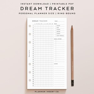 May include: A white Dream Tracker planner insert with a grid layout for daily entries, designed for personal use. The planner includes sections for tracking dreams, with prompts for emotions and notes. A wooden pencil rests beside the planner.
