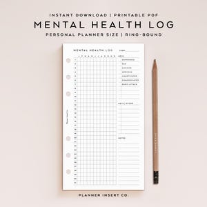 May include: A white Mental Health Log planner insert with a grid layout for daily tracking. The planner includes sections for recording feelings and notes, with the text "Mental Health Log" at the top. A wooden pencil rests beside the planner.
