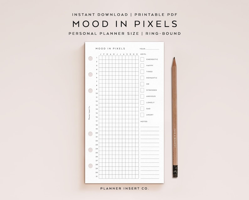 May include: A white planner insert with a grid for tracking mood, labeled "MOOD IN PIXELS." The insert has pre-printed sections for the year, month, and mood keys. A wooden pencil rests beside the planner. Text at the top reads "INSTANT DOWNLOAD | PRINTABLE PDF."
