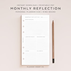 May include: A white planner insert with the text "MONTHLY REFLECTION" and lined sections for notes. A wooden pencil rests beside the planner. The text "INSTANT DOWNLOAD | PRINTABLE PDF" is at the top. The planner is ring-bound.