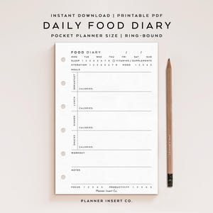 May include: A white Daily Food Diary printable PDF with a ring-bound design. The planner includes sections for meals, sleep, hydration, and mood tracking. A wooden pencil rests beside the planner.