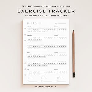 May include: A white exercise tracker planner with the text "Exercise Tracker" and "A5 PLANNER SIZE | RING-BOUND". The planner has sections for each month, with spaces to track exercise. A wooden pencil rests on the right side.