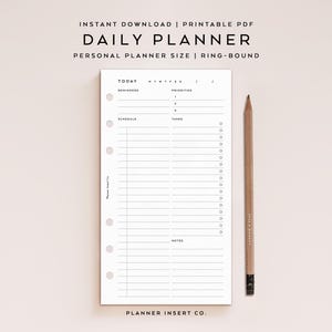 Op de afbeelding: Een witte dagplanner-inlegger met een ringbandontwerp, met secties voor herinneringen, prioriteiten, schema, taken en notities. Een houten potlood ligt naast de planner. De tekst luidt "DAILY PLANNER" en "PLANNER INSERT CO."