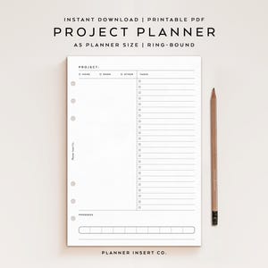 May include: A white A5 ring-bound project planner page featuring a project title line, checkboxes for home, work, and other, a task list with checkboxes, a progress section with eight boxes, and a wooden pencil placed to the right of the page.