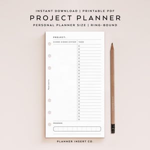 May include: A white project planner insert with the text "PROJECT PLANNER" and "PERSONAL PLANNER SIZE | RING-BOUND". The planner has sections for tasks and progress tracking, with a wooden pencil resting beside it.