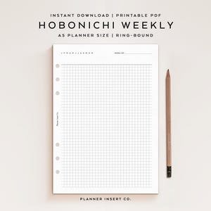 Könnte beinhalten: Ein weißer Hobonichi Weekly A5 Planereinsatz mit Rastermuster, Ringbindung und Bleistift. Der Text auf dem Einsatz lautet "HOBONICHI WEEKLY" und "A5 PLANNER SIZE | RING-BOUND". Der Bleistift ist braun.