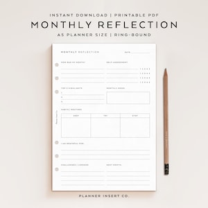 May include: A white A5 planner insert with the text "MONTHLY REFLECTION" and sections for self-assessment, highlights, and habits. A wooden pencil rests beside the planner. The text "INSTANT DOWNLOAD | PRINTABLE PDF" is at the top.