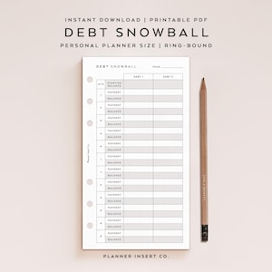 May include: A white printable personal planner insert for tracking a debt snowball, featuring columns for debt 1 and debt 2, monthly rows for starting balance, payment, and balance, with six ring-bound holes on the left side and a wooden pencil.