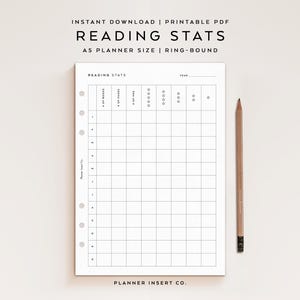 May include: A white A5 ring-bound planner insert titled READING STATS with a grid for tracking books, pages, hours, and star ratings by month. The page features six circular binder holes on the left side and a wooden pencil placed to the right.