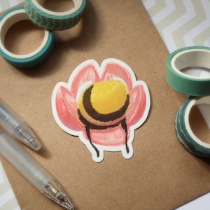 Può includere: Un adesivo di un'ape con strisce nere e gialle, all'interno di un fiore rosa. L'ape è rivolta verso lo spettatore e ha un addome giallo. Il fiore è un fiore rosa stilizzato con cinque petali.