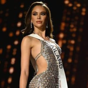 May include: A woman wearing a silver sequined gown with a sash that reads "THAILAND".