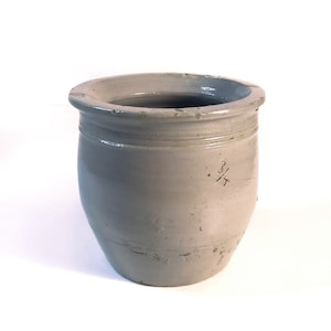 Peut inclure: Un pot en céramique blanche avec un corps arrondi et une large ouverture. Le pot a un design simple et est marqué du numéro "3/4" sur le côté.