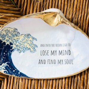 May include: White seashell dish with a gold rim and a blue and white wave design. The dish has the text "And into the ocean I go to lose my mind and find my soul" printed on it.