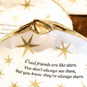 May include: White ceramic dish with a gold rim and gold star accents. The dish has a quote about friendship: "Good friends are like stars. You don't always see them, but you know they're always there."