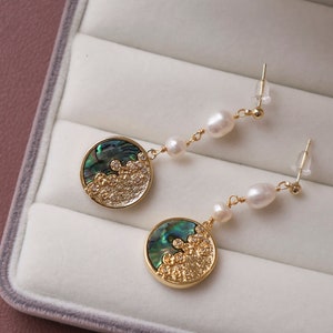 Puede incluir: Un par de pendientes de oro con un diseño redondo de concha de abulón verde y blanco y una perla colgante.