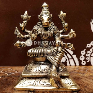 May include: A gold-colored metal statue of a Hindu deity with a boar head, sitting on a lotus pedestal. The deity has multiple arms and is adorned with intricate details.