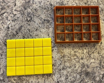 May include: A yellow silicone mold with 25 square sections, and a brown plastic mold with 25 square sections.